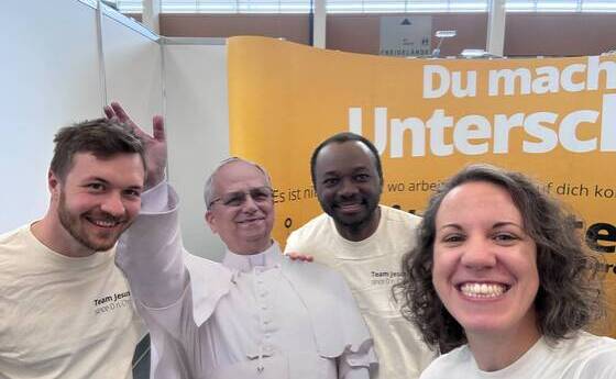 V. l.: Samuel Hanner, Papst Leo, Maximus Nwolisa und Stefanie Brandstetter beim Stand der Katholischen Kirche in Oberösterreich auf der Messe 'Jugend & Beruf'.