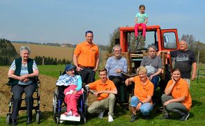 Caritas-Haustechniker Thomas Schmid (stehend, im orangen T-Shirt) mit dem 'Arbeitstrupp'.
